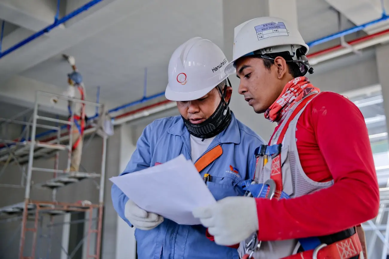 Deux professionnels du bâtiment examinant des plans sur un chantier