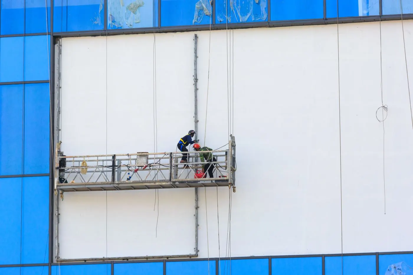 Nacelle de chantier devant une façade d'immeuble en cours de ravalement